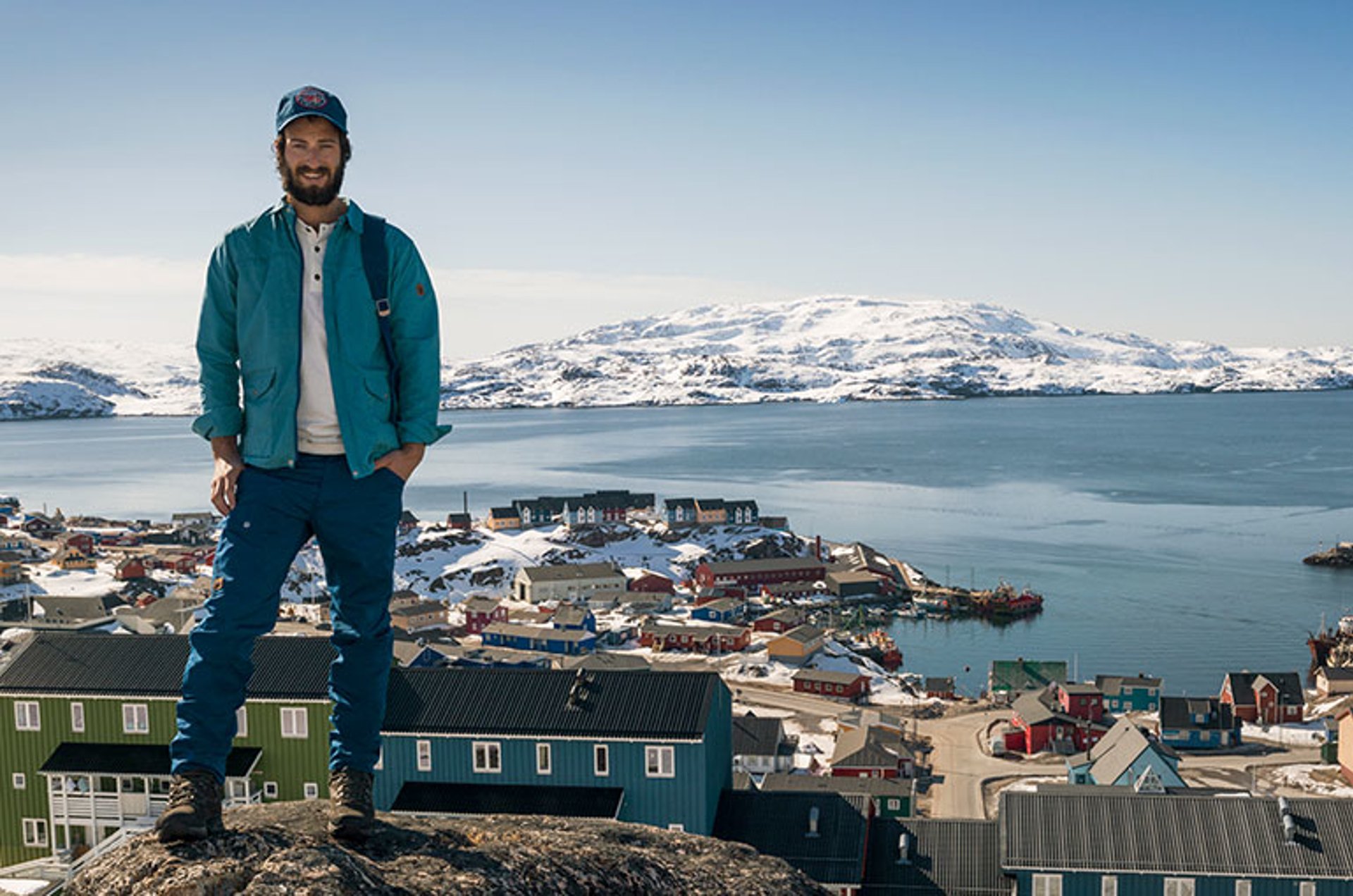 Man standing on hillside overlooking small colorful Scandinavian town